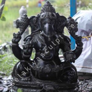 A Vinayaga garden sculpture made of stone. The sculpture depicts the Hindu god Vinayaga, who is the remover of obstacles. He is shown with a human body and the head of an elephant. He is holding a veeramoksham (axe), a modak (sweetmeat), and a rudraksha mala (rosary). The sculpture is placed in a garden setting.